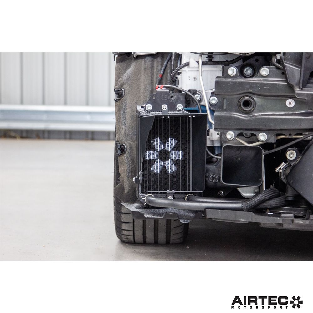 AIRTEC Motorsport auxiliary radiator installed in a Toyota Yaris GR Gen2, showing the sleek black radiator with mounting brackets.