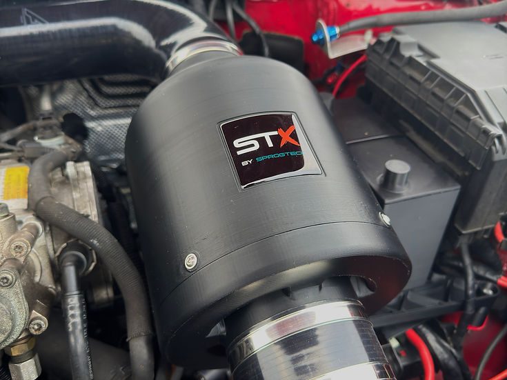 SprogTech STX EA3 enclosed intake kit for 2.0 TFSI engines, installed in a vehicle, showcasing sleek body and styling features.
